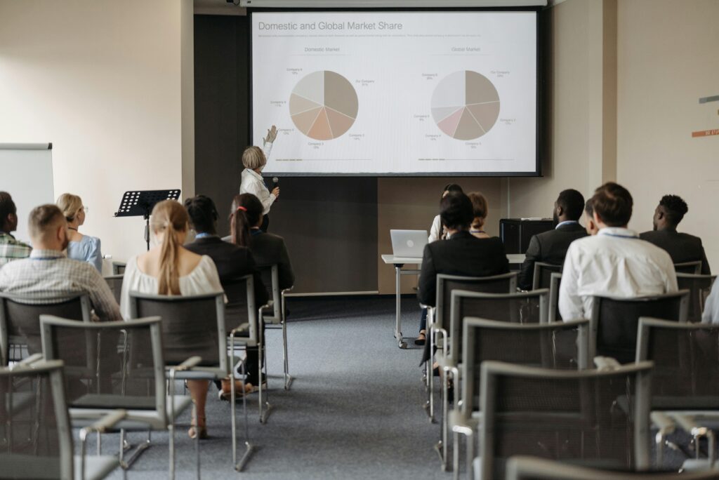 Business conference with diverse audience and speaker presenting market data.
